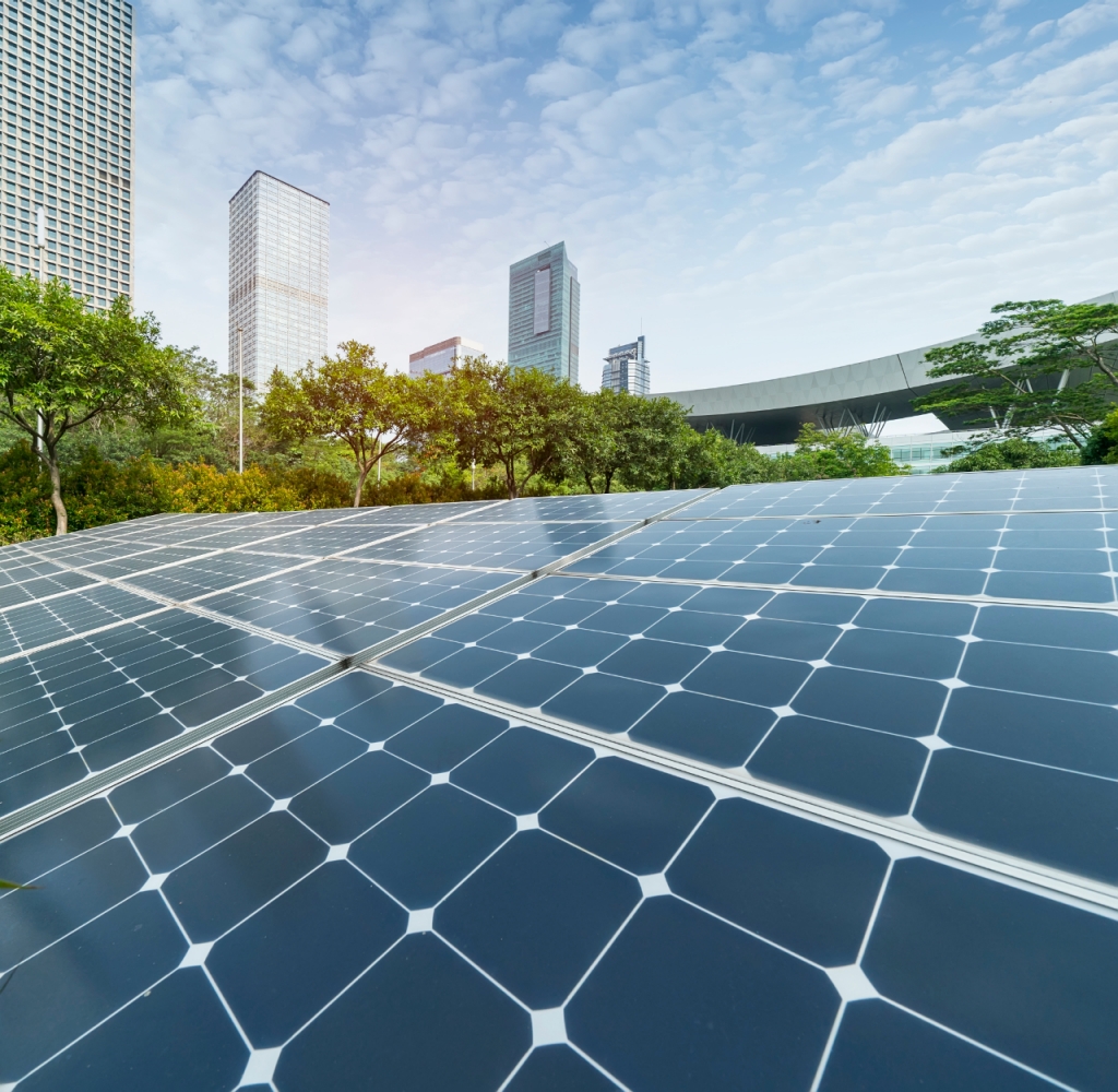 Close-up of solar panels with trees and a city in the background