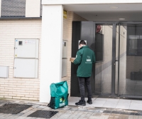 A Koiki delivery person enters a doorway
