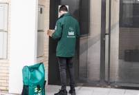 A Koiki delivery person enters a building with a package