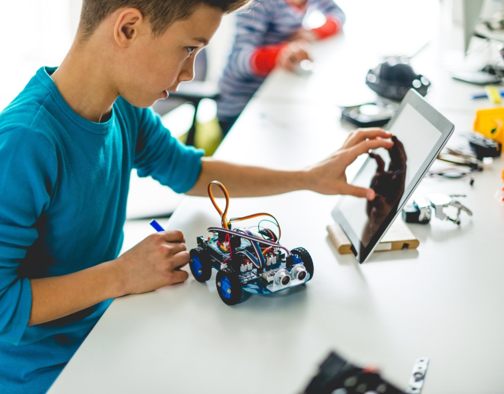 A boy operates a tablet in a robotics lab at a school