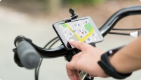 A hand clicks on a map on a cellphone that is attached to the handlebars of a bicycle