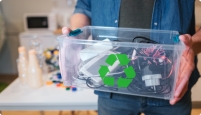 A man holds a transparent box with different electronic devices for recycling